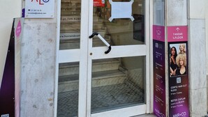 A building entrance with a glass door, signs for a dental clinic, and a hair salon. - Bons Dias (Lisbon)