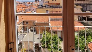 A view from a window overlooking a cityscape with buildings, a tower, and a clear sky. - Bons Dias (Lisbon)