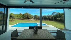 Un patio cubierto con piscina, mobiliario exterior y vistas del paisaje circundante.