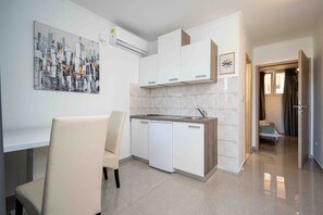 Modern kitchen with dishwasher and sink, adjacent to a dining area with a single chair.