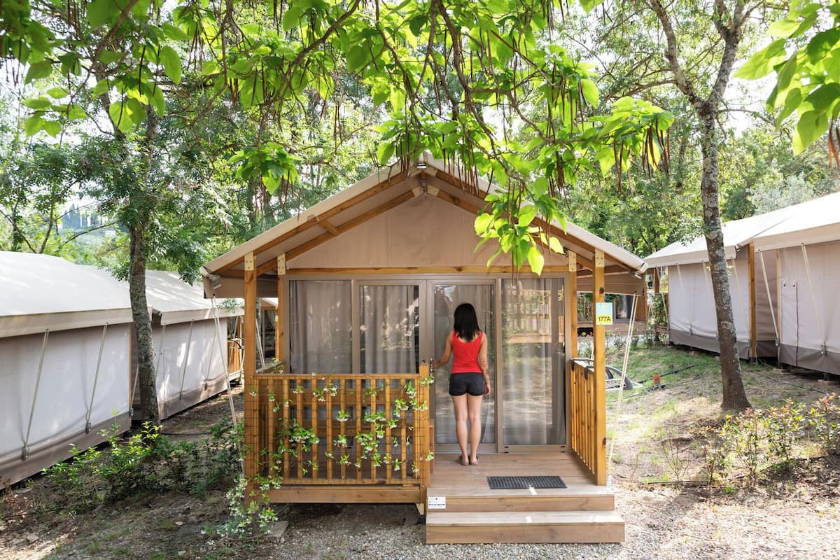 Een klein houten vakantiehuisje met een balkon, omringd door bomen en andere gelijksoortige accommodaties.