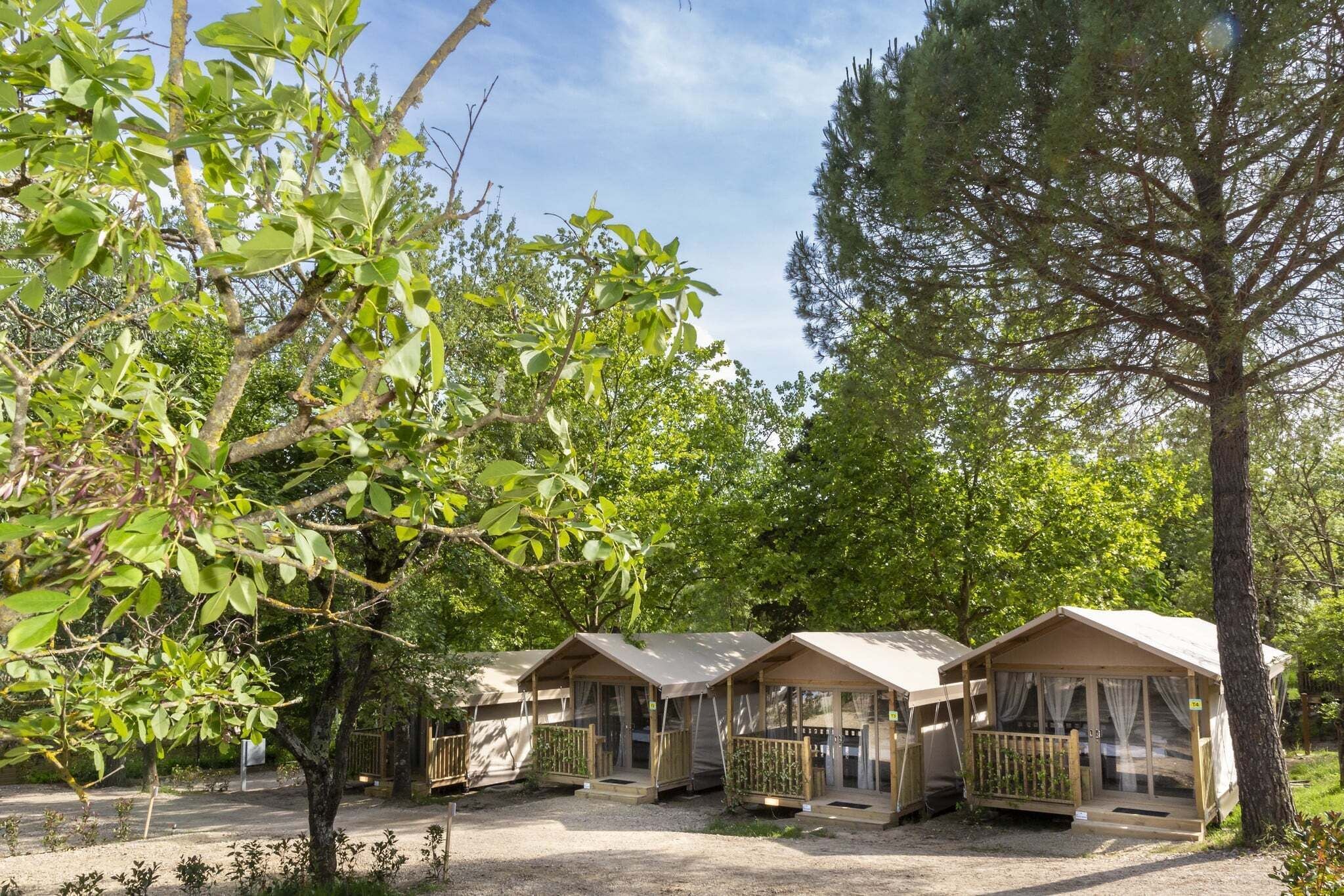 A row of small, single-story cabins with wooden railings and a gravel ground.