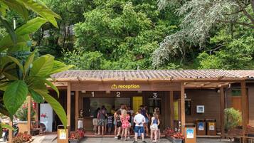A reception area with numbered doors, a sign indicating reception, and people standing outside.