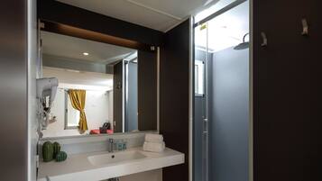 A modern bathroom with a large mirror, a white sink, and a shower area.