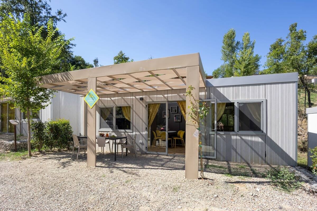 Een moderne buitenpatio met een pergola, een eettafel met stoelen en een kleine tuin.