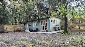 Una casa pequeña con porche, rodeada de bosque.