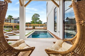 Uma área de piscina com cadeiras de vime e vista para um edifício do outro lado da piscina.