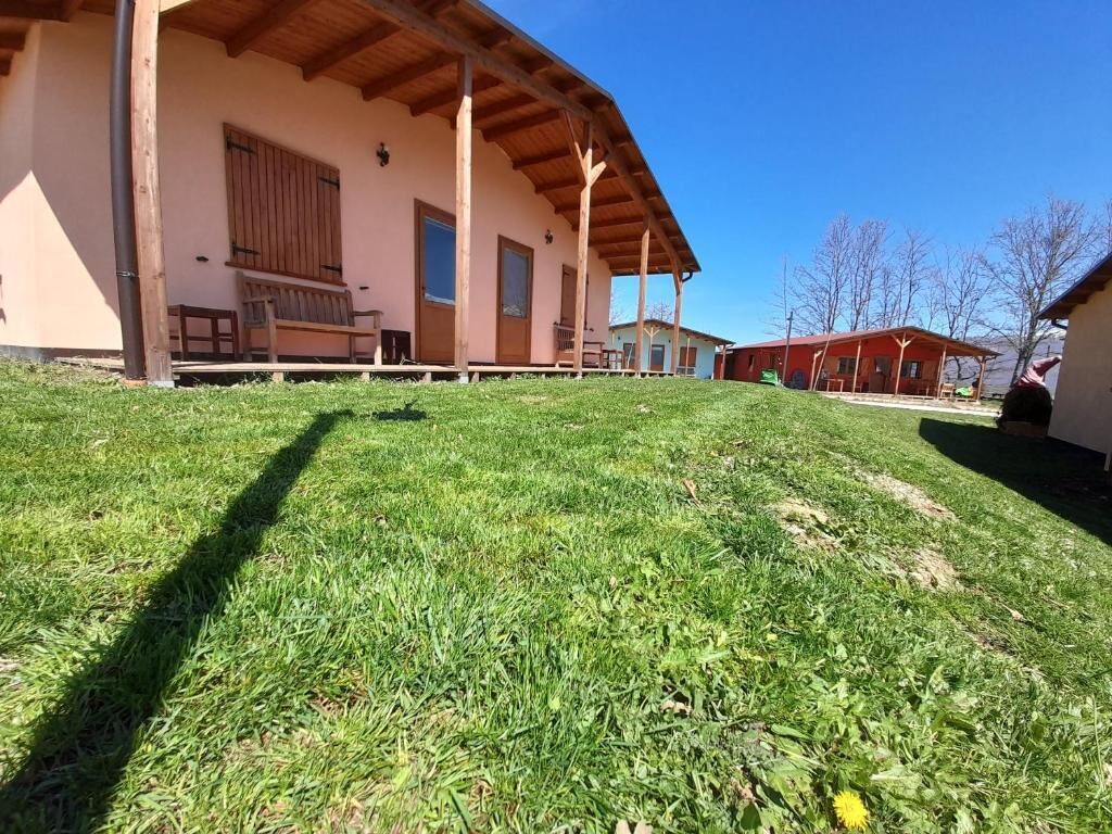 A building with a wooden porch and a grassy lawn.