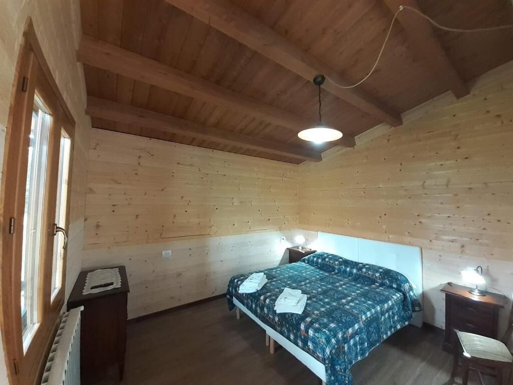 A wooden-paneled room with a bed, two bedside tables, and a window.