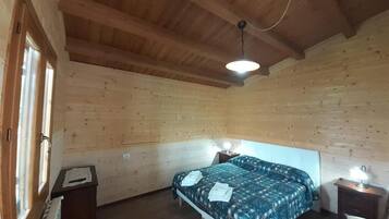 A wooden-paneled room with a bed, two bedside tables, and a window.