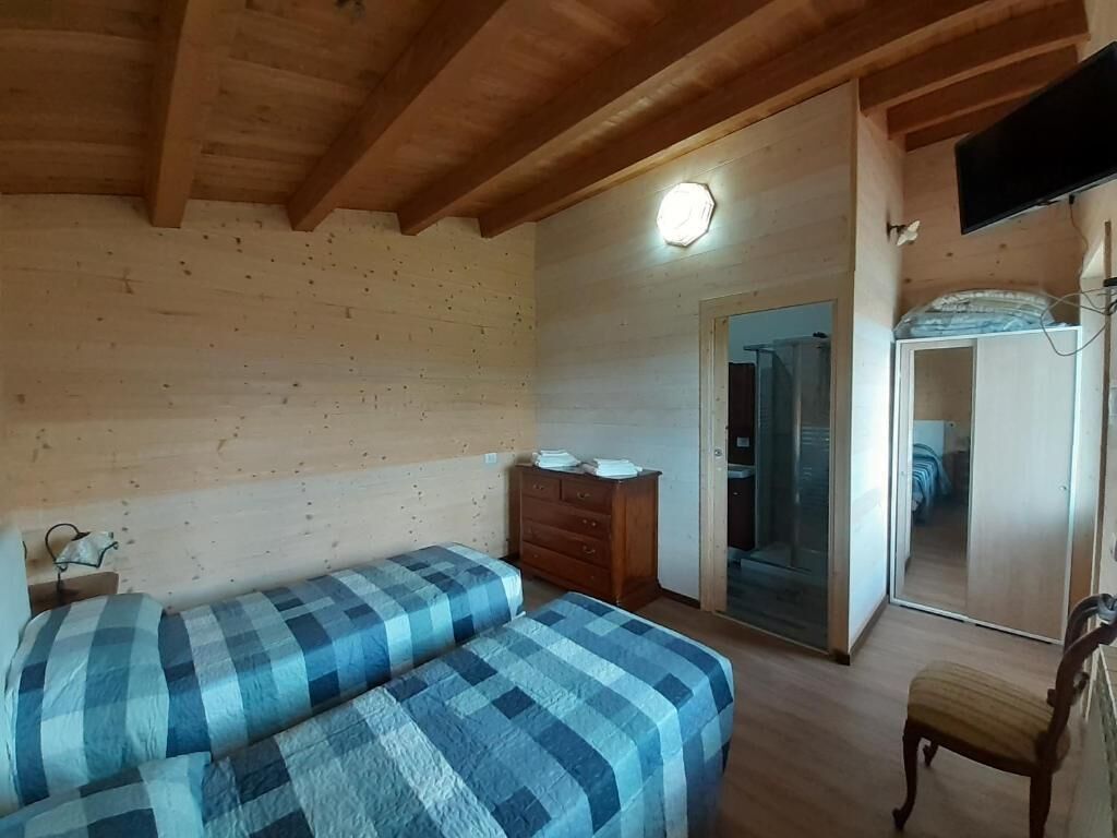 Une chambre avec deux lits, un plafond en bois, une commode, un miroir et un téléviseur.