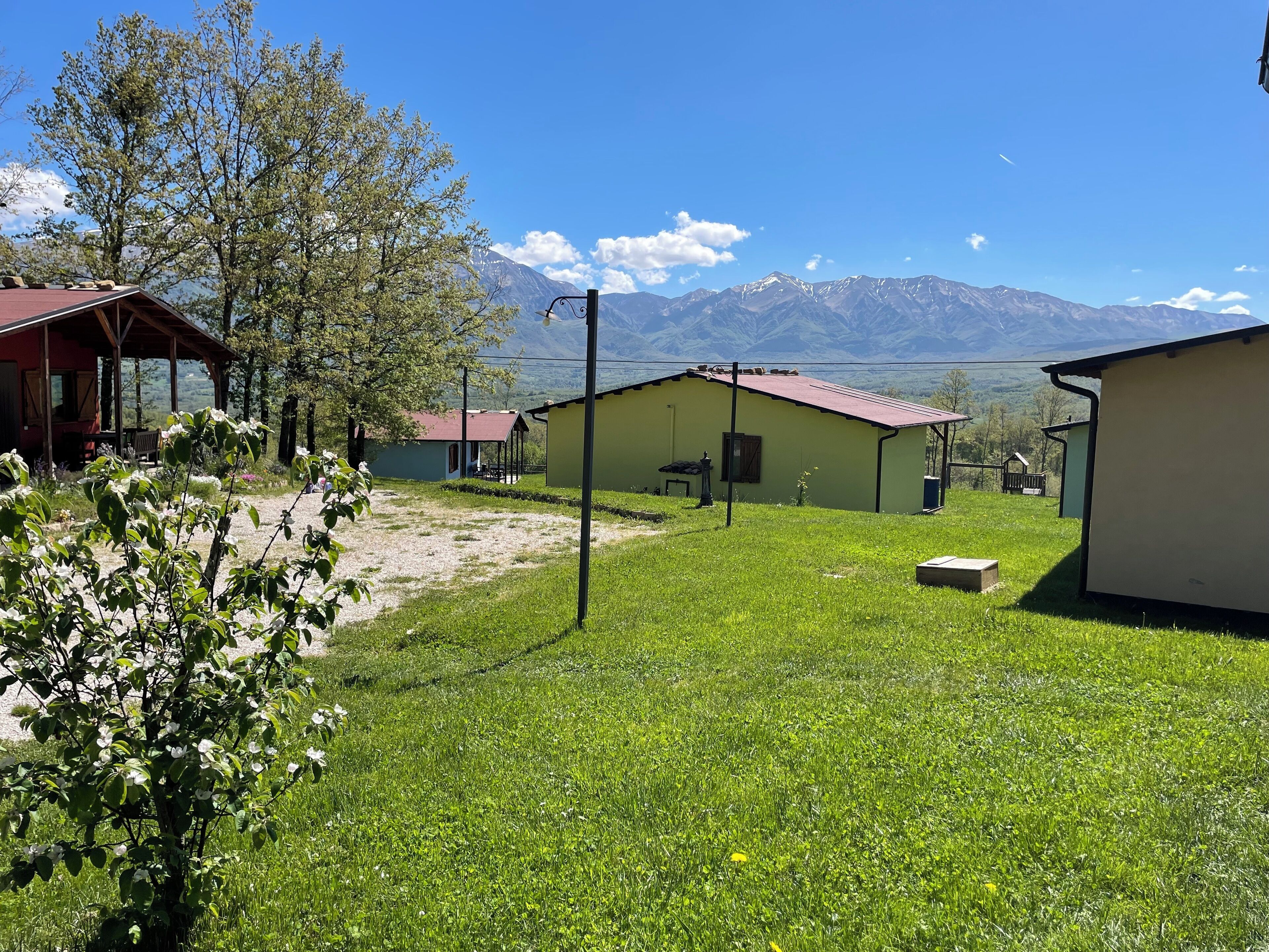 Um cenário rural com uma casa pequena, um alpendre coberto e vista para montanhas distantes.