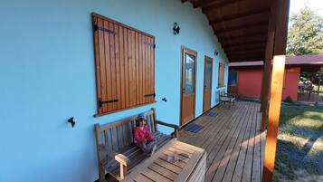 A covered wooden deck with a bench and a child sitting on it.