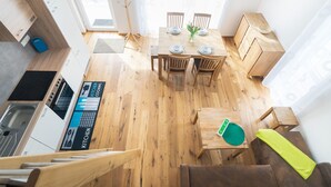 Une cuisine moderne avec un plancher en bois, un coin repas avec une table dressée pour quatre personnes, et un escalier menant à un autre niveau.