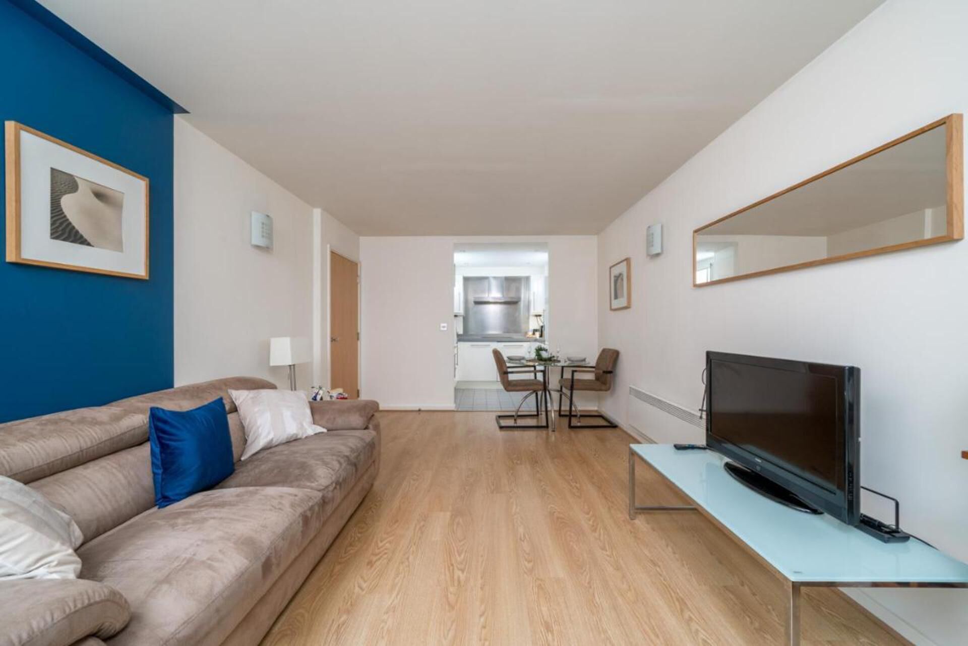 A modern living room with a sofa, a TV, and a dining area with chairs and a table.