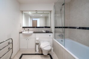Ein modernes Badezimmer mit einer Duschkabine, einem weißen Waschbecken und einer Toilette.