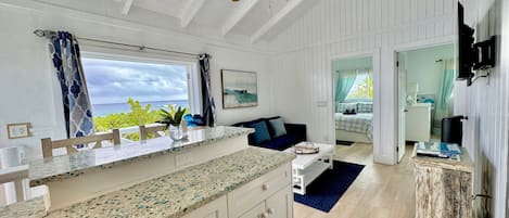A spacious kitchen with a large island, a ceiling fan, and a view of the ocean through a window.