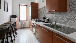 A modern kitchen with wooden cabinets, a stainless steel sink, and a tiled backsplash. - New Fashion District 3 BDRS (Milano)