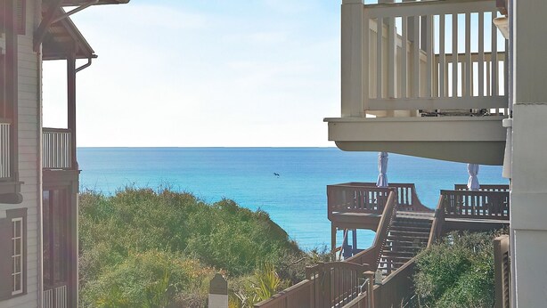Blick aufs Meer vom Balkon mit Holzterrasse und Treppe zu einer höheren Ebene.