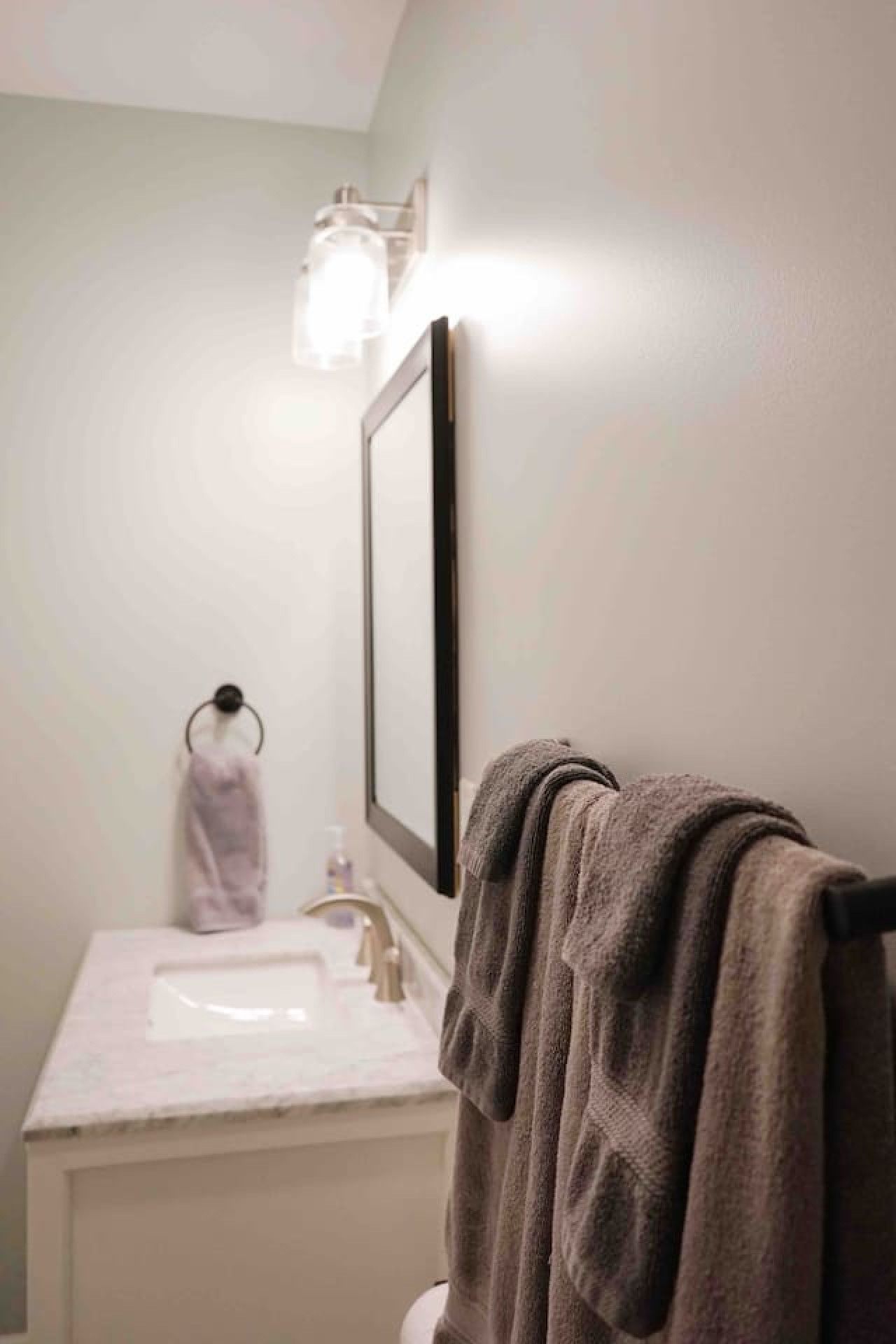 Ein Badezimmer mit Waschbecken, Spiegel, Handtuchhalter und einem Handtuch.