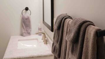 Ein Badezimmer mit Waschbecken, Spiegel, Handtuchhalter und einem Handtuch.