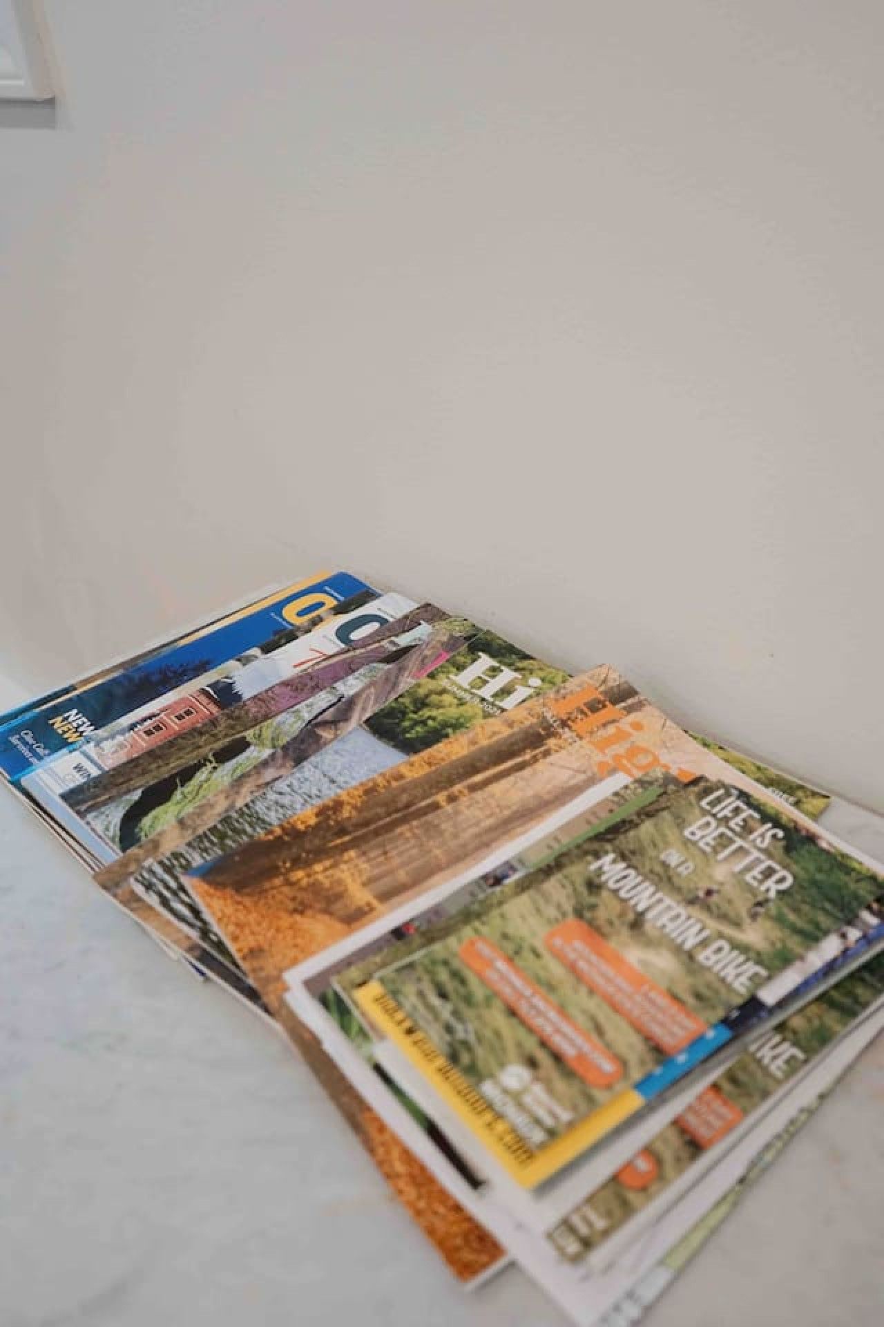 A stack of magazines with visible titles and images of landscapes and buildings.