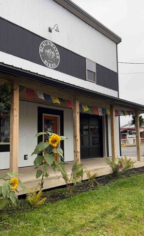 Un bâtiment sur lequel on peut lire l’inscription « Blackwater Bikes », et une véranda décorée de drapeaux aux couleurs vives.