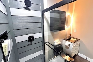 Een badkamer met een glazen douchecabine, een wastafel en een handdoekrek.