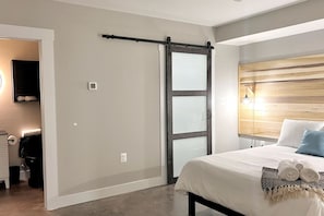Een slaapkamer met een bed, een schuifdeur, een houten hoofdbord en een bedlamp.