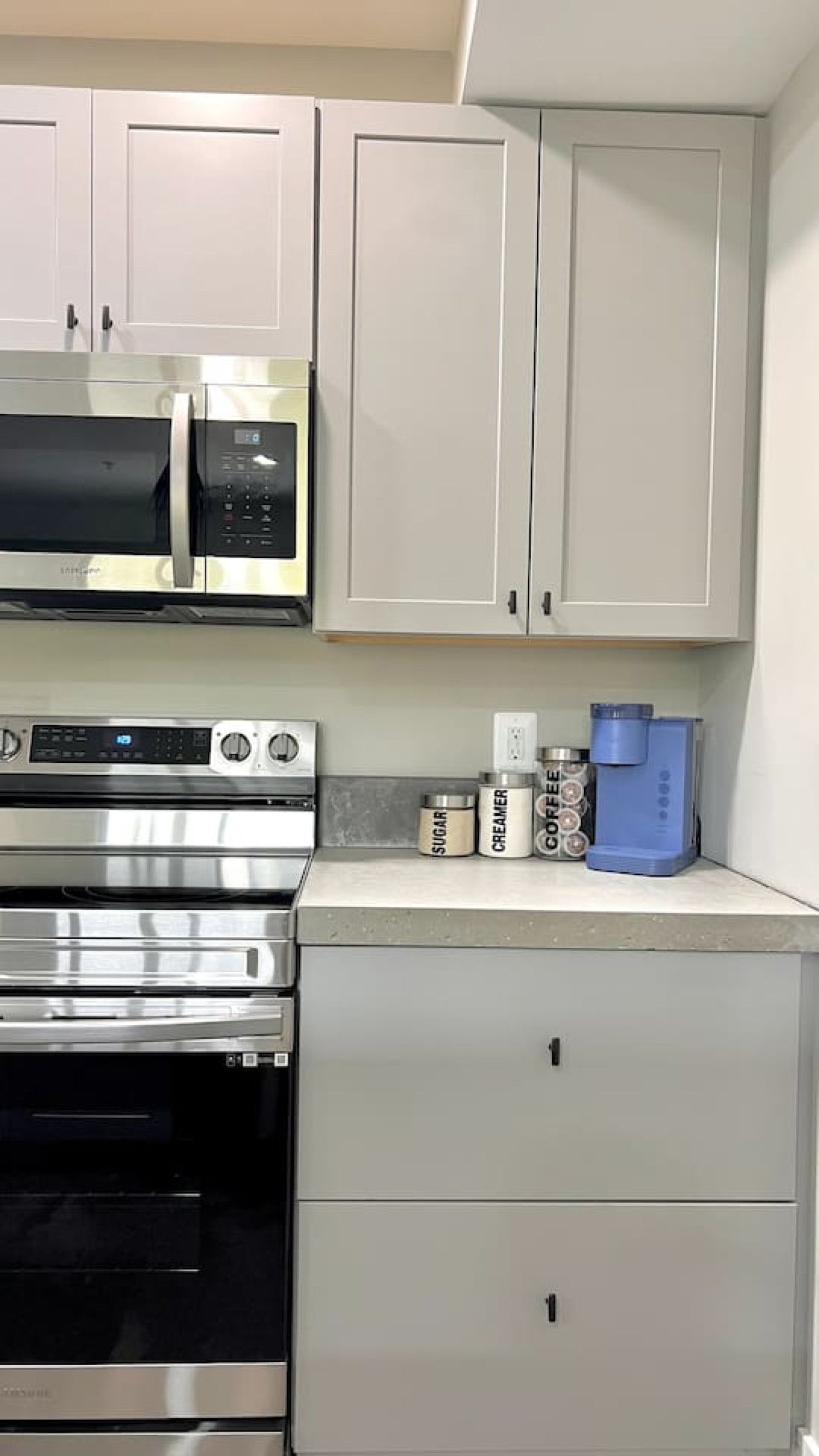 A kitchen with stainless steel appliances, including a microwave and oven, and light-colored cabinetry.