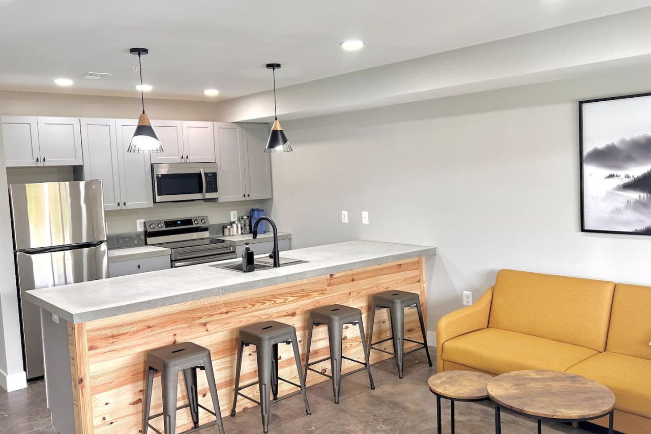 A modern kitchen with a central island, bar stools, a microwave, and stainless steel appliances.