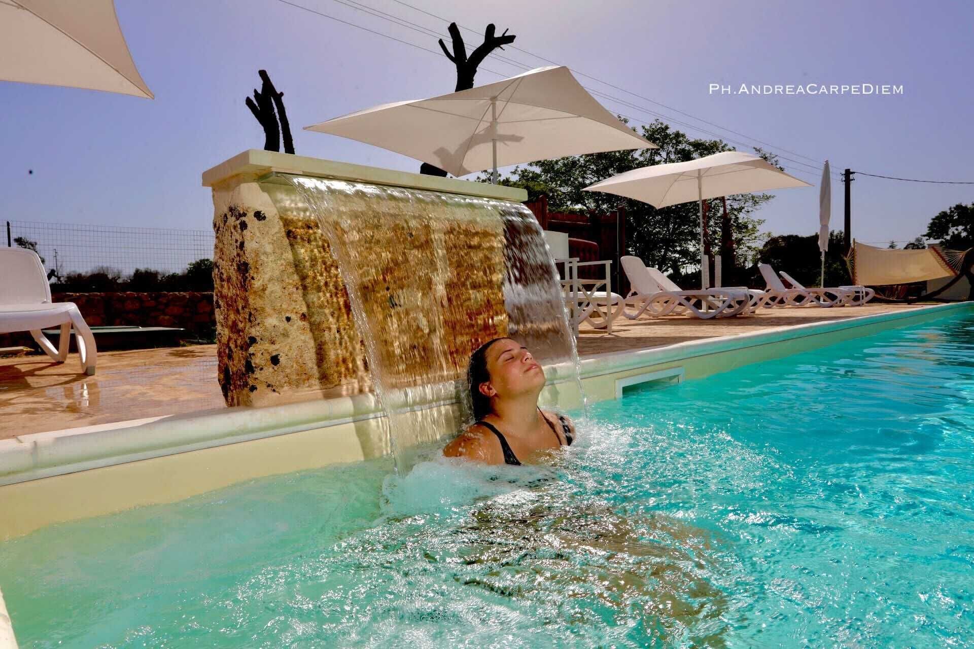 Una donna nuota in piscina con una cascata.