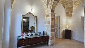 A room with a stone ceiling, a large mirror, a wooden dresser, and a lamp. - Luxury B&B Casina il Mandorlo (Nardò)