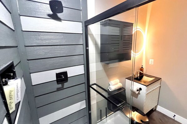 A bathroom with a glass enclosure, a sink, and a towel rack.