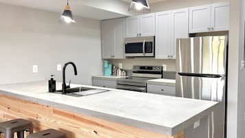 Una cocina moderna con una isla central, electrodomésticos de acero inoxidable y taburetes de madera.