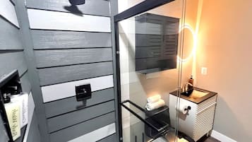 Een badkamer met een glazen douchecabine, een wastafel en een handdoekrek.