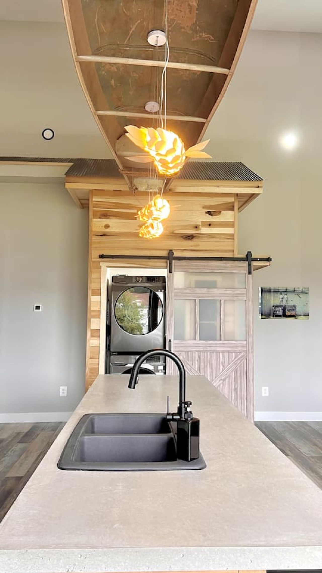 A modern kitchen with a central island, a black faucet, and a ceiling fan with light fixtures.