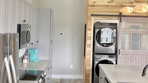 Une cuisine moderne dotée d’appareils électroménagers en acier inoxydable, de meubles de rangement en bois et d’un four encastré.