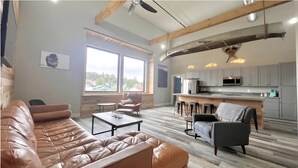 Un salon moderne avec un canapé en cuir, une table basse et un coin repas équipé de tabourets de bar.
