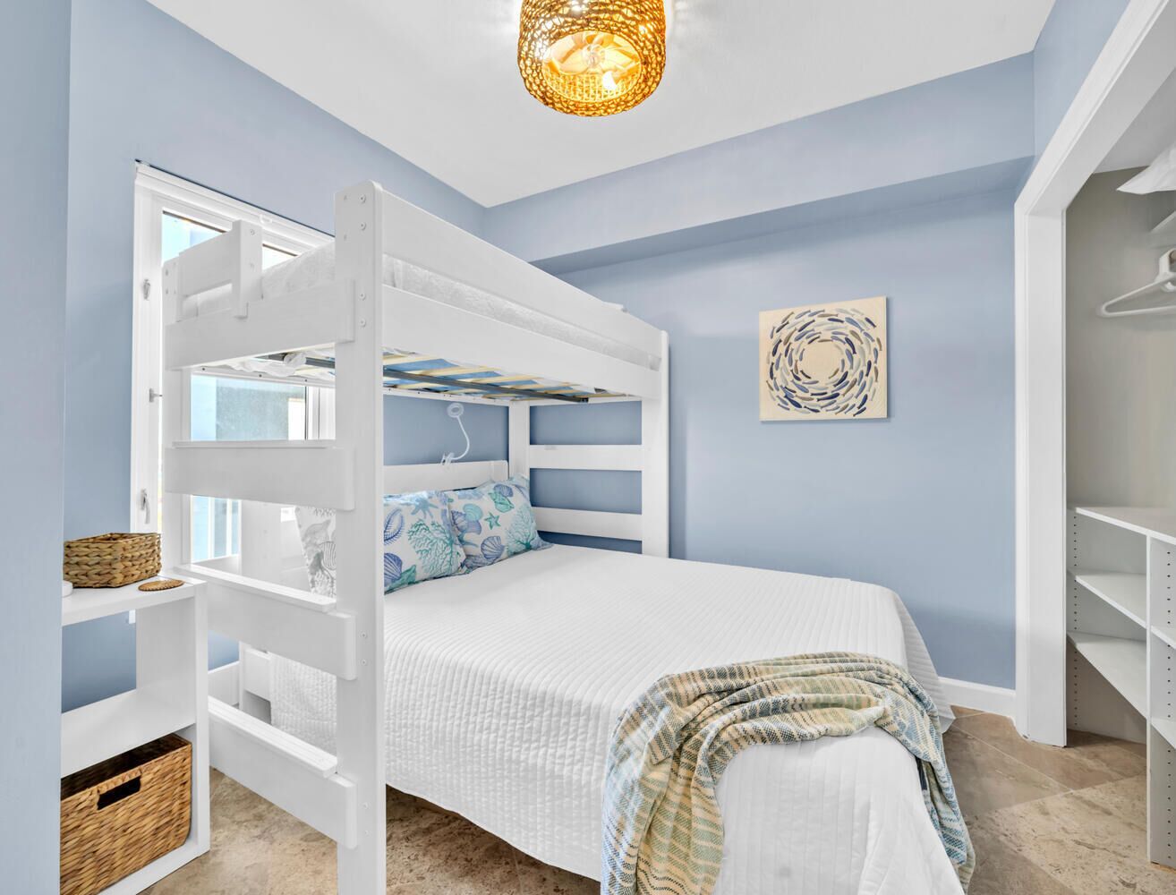 A bedroom with a bunk bed, a white wardrobe, a hanging light fixture, and a wall art piece.