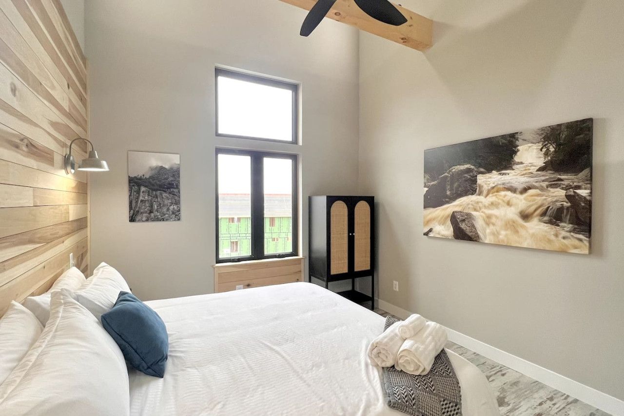 A bedroom with a bed, a window, and two wall-mounted artworks.