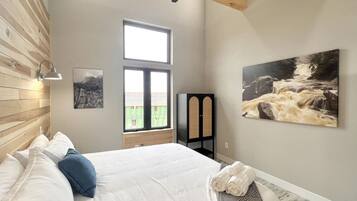 A bedroom with a bed, a window, and two wall-mounted artworks.