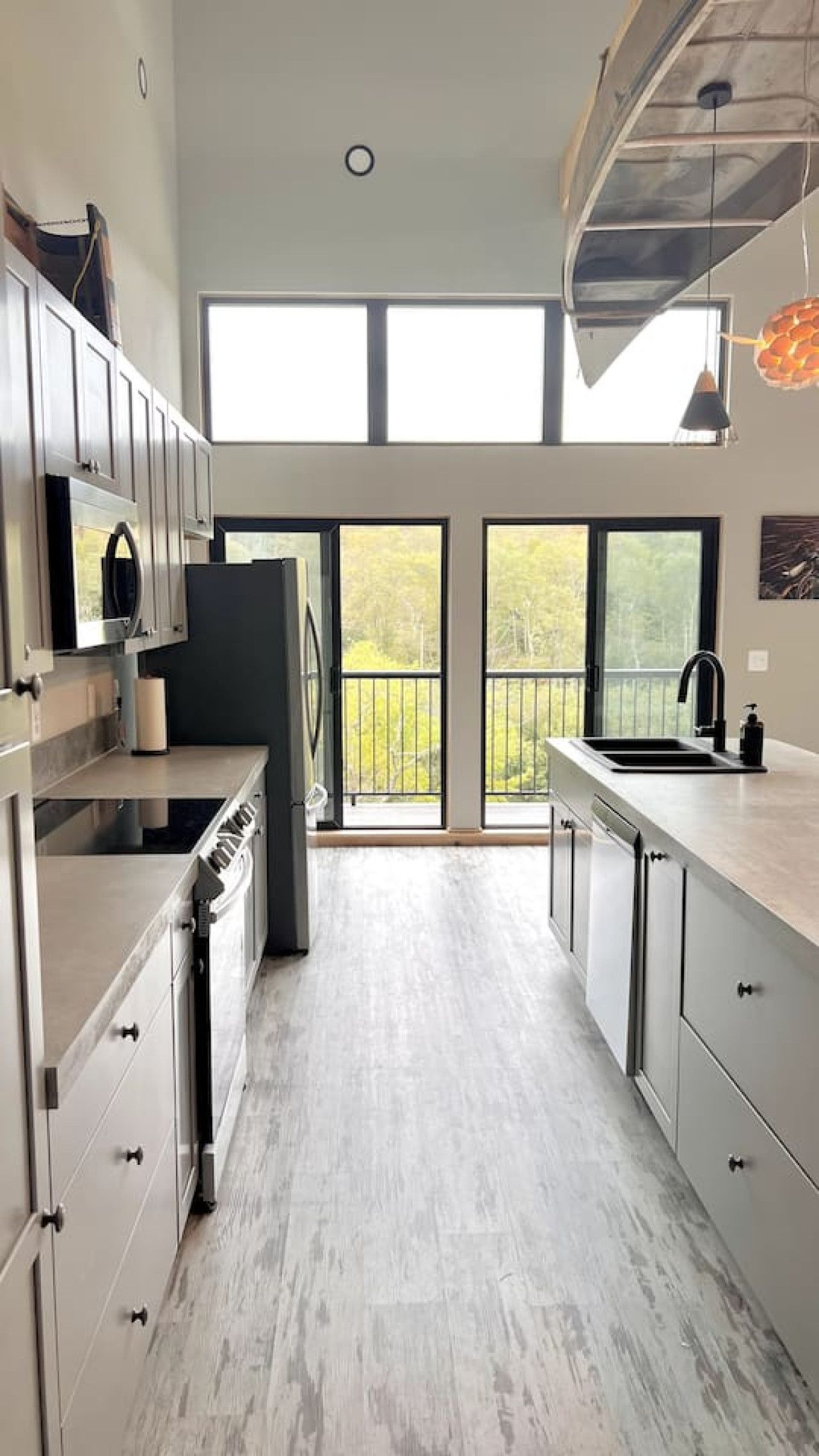 A modern kitchen with a central island, large windows, and a view of the outdoors.