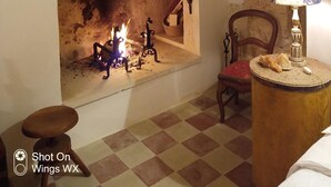 A room with a fireplace, a checkered floor, a wooden chair, and a lamp on a side table. - loft Salento Style (Alessano)