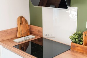 A kitchen with a wooden countertop, a cutting board, a white plate, and a green wall. - Villa Selva, Beach 500 m Away (Sérignan)
