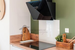 A kitchen with a modern stove, a wooden cutting board, and a small plant on the counter. - Villa Selva, Beach 500 m Away (Sérignan)