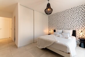 Une chambre à coucher avec un lit, une armoire, un mur à motifs et un luminaire suspendu.