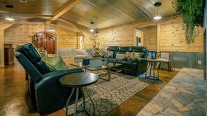 A log cabin interior with a leather sofa, a coffee table, and a hanging plant.
