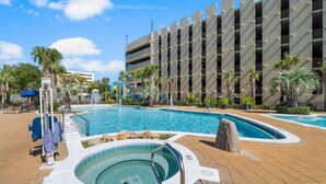 Un hotel con una amplia piscina exterior, un jacuzzi y una estructura de estacionamiento de varios niveles.
