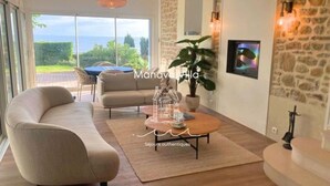 A modern living room with a sofa, coffee table, and a view of the outdoors.